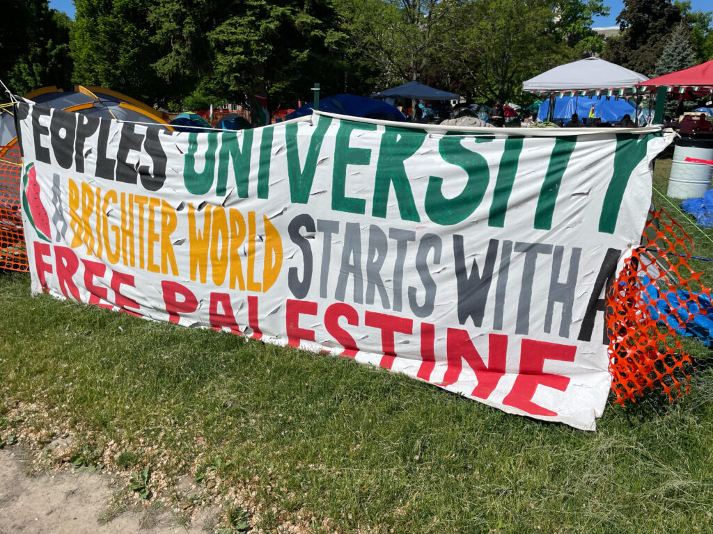 A picture of a large banner painted on cloth that states "People's university: A Brighter World Starts with a Free Palestine."