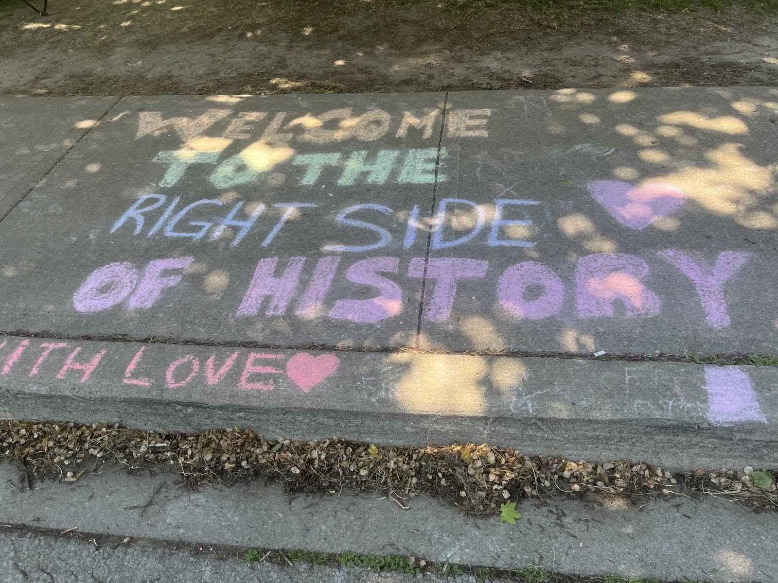 An image of text written on the sidewalk in chalk stating "Welcome to the right side of history"